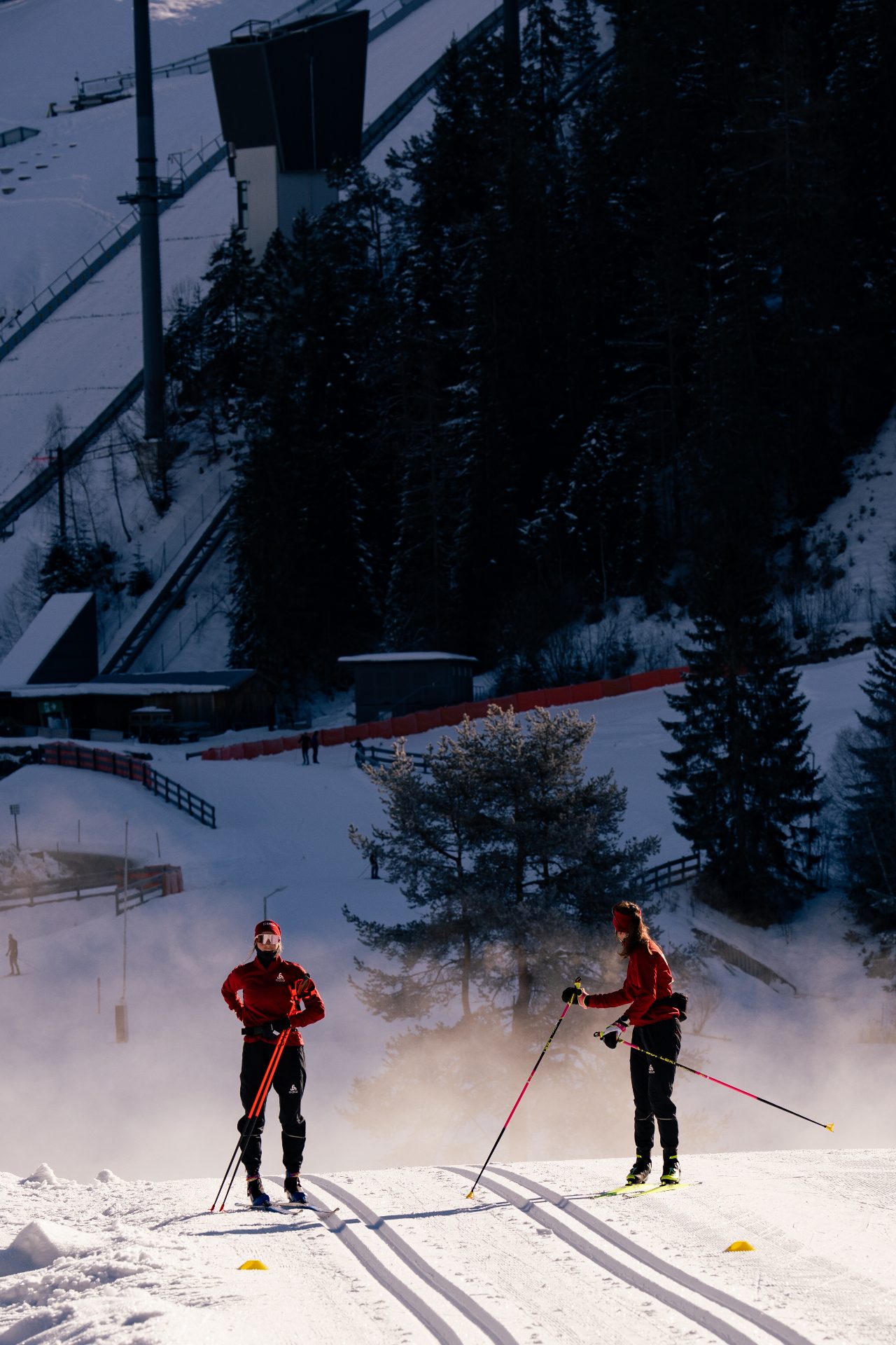 Zwei Langläuferinnen im Training vor einer Skisprungschanze